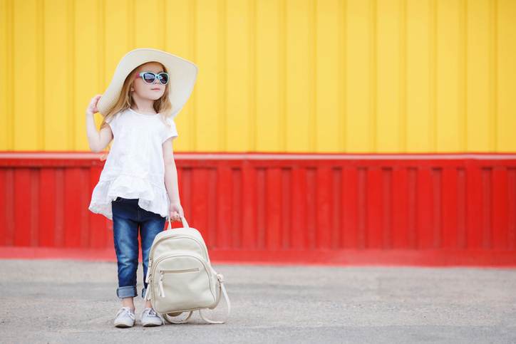 Little schoolgirl with a white backpack